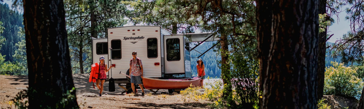 family of three getting reading to relax beside a Springdale travel trailer